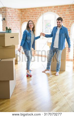 Young couple moving to a new home, having fun riding a skateboar