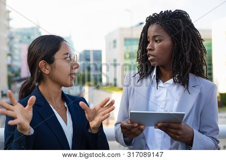 Coworkers Talking And Using Tablet Pc. Young Multiethnic Businesswomen Holding Digital Tablet And Lo