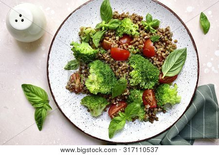 Buckwheat Salad With Vegetables On A White Plate Over Light Pink Slate, Stone Or Concrete Background