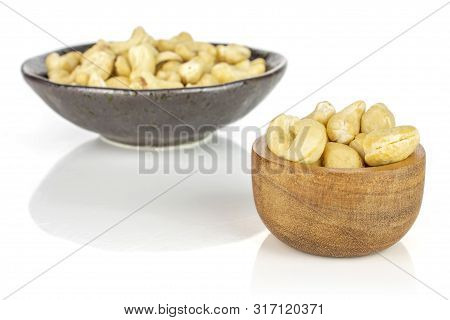 Lot Of Whole Unsalted Beige Cashew In Tiny Wooden Bowl In Dark Ceramic Bowl Isolated On White Backgr