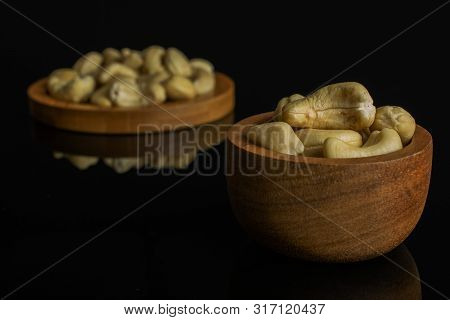 Lot Of Whole Unsalted Beige Cashew On Round Bamboo Coaster In Tiny Wooden Bowl Isolated On Black Gla