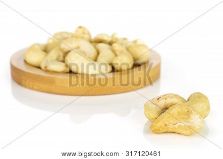 Lot Of Whole Unsalted Beige Cashew On Round Bamboo Coaster Isolated On White Background