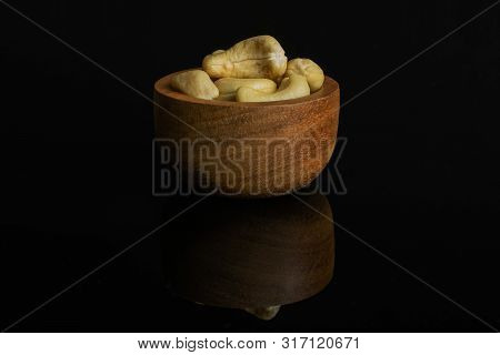 Lot Of Whole Unsalted Beige Cashew In Tiny Wooden Bowl Isolated On Black Glass