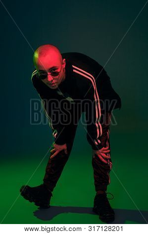 Studio Shot Of A Young Tattoed Bald Man Posing Against A Colorful Background. 90s Style.
