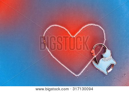 Beads Of Rock Crystal Laid Out In The Shape Of A Heart On A Blue Background. Nearby Is A Lockable Lo