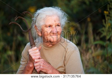 A Closeup Portrait Of An Old Woman With Gray Hair Smiling And Looking Up, Resting Her Chin On A Stic