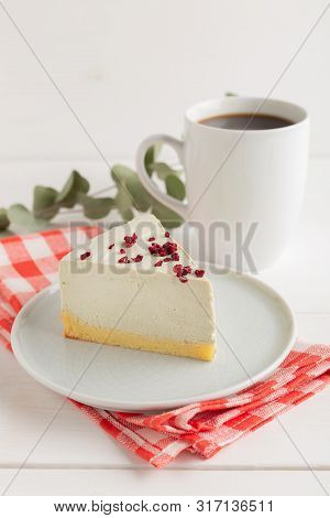 Piece Of Cheesecake On Gray Plate On Kitchen Spatula And Cup Of Coffee On Background
