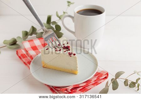 Piece Of Cheesecake On Gray Plate On Kitchen Spatula And Cup Of Coffee On Background