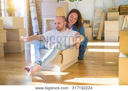 Funny and crazy couple having fun riding a cardboad box as a car, smiling happy and lauging at new home