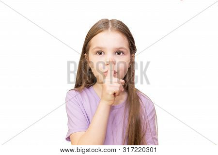 The Little Girl Put Her Index Finger To Her Mouth. Isolated On A White Background. For Any Purposes