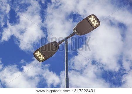 Three Led Street Lamps Affixed To An Iron Post Against A Deep Blue Sky