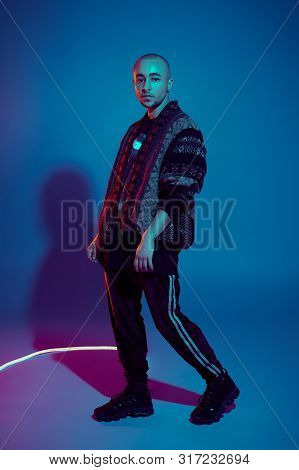 Studio Shot Of A Young Tattoed Bald Man Posing Against A Colorful Background. 90s Style.