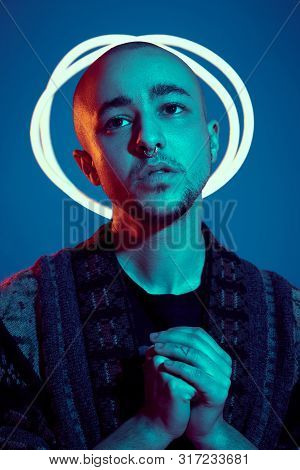 Studio Shot Of A Young Tattoed Bald Man Posing Against A Blue Background. 90s Style.
