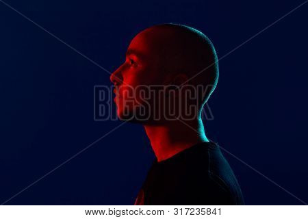 Studio Shot Of A Young Tattoed Bald Man Posing Against A Blue Background. 90s Style.
