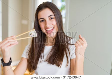 Beautiful young woman eating asian sushi using chopsticks screaming proud and celebrating victory and success very excited, cheering emotion