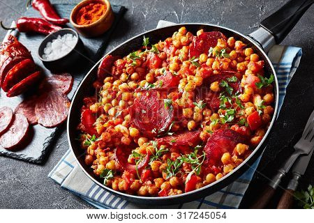 Close-up Of Garbanzos Fritos, Stewed Chickpeas With Chorizo, Ham, Tomatoes And Spices In A Skillet O
