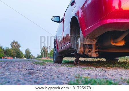 Flat Tire Car Service Concept. Car Standing In The Side Of The Road With One Wheel Taken Off. And Li