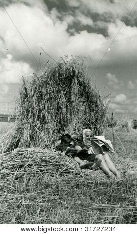 Foto vintage de mãe e filha lendo jornais sob um feixe (anos 50)
