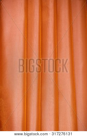 Vertical Folds On Orange Organza Curtains For Background And Design