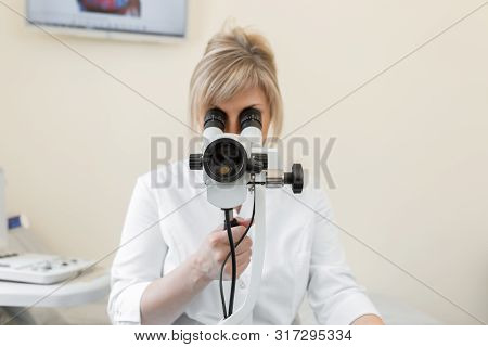 Young Female Professional Gynecologist In The Working Process, Looks Into The Colposcope.