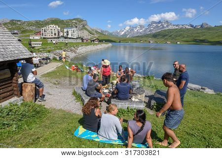 Group Of Happy People Frying Meet On Barbeque Grill At Melchsee-frutt On The Swiss Alps