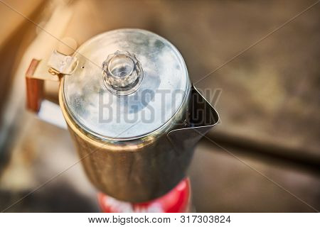 Travel Kettle On The Primus Fire. Close Up Of A Stainless Kettle Over Morning Sunlight. Making Coffe