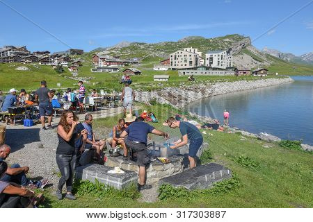 Group Of Happy People Frying Meet On Barbeque Grill At Melchsee-frutt On The Swiss Alps
