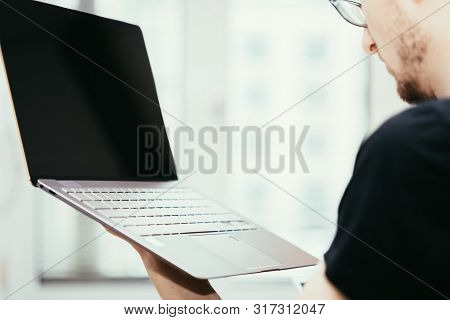 Young Freelancer Is Holding Up A Thin Elegant Notebook