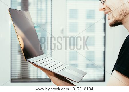 Young Freelancer Is Holding Up A Thin Elegant Notebook