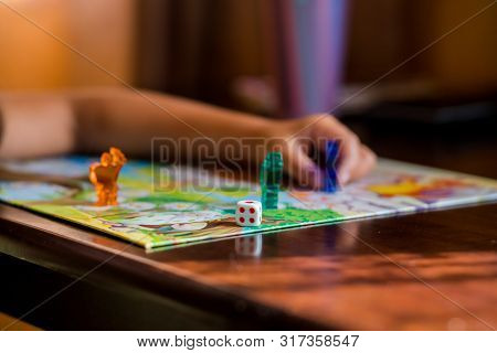 Multi-colored Game Chips With Dice On The Playing Board. Board Game.children Sit In Kindergarten At 