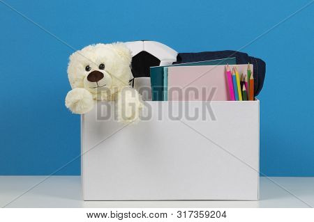 Donation Box With Toys, Books, Clothing For Charity Over Blue Background