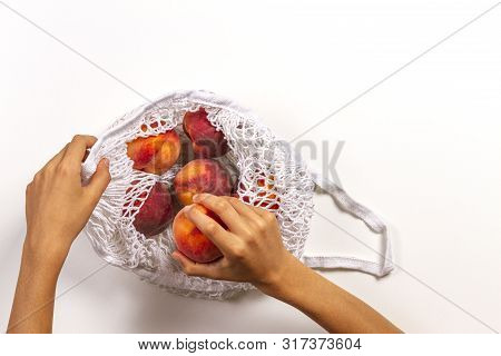 Top View To Kis Hands Putting Peaches In Mesh Glocery Shopping Bag On White Background