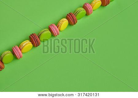 Colored Macaron Or Macaroon, Sweet Meringue-based Confection On Green Background. Close-up, Copy Spa