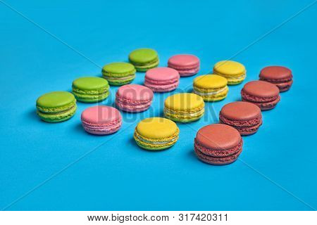 Colored Macaron Or Macaroon, Sweet Meringue-based Confection On Blue Background. Close-up, Copy Spac