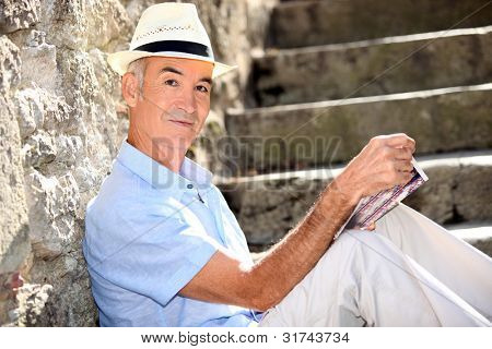Pensionerad man läsa hans guidebok