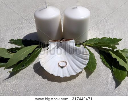 Seashell With Ring In It On White Table Ith Candles And Decorations. Engagement Ring
