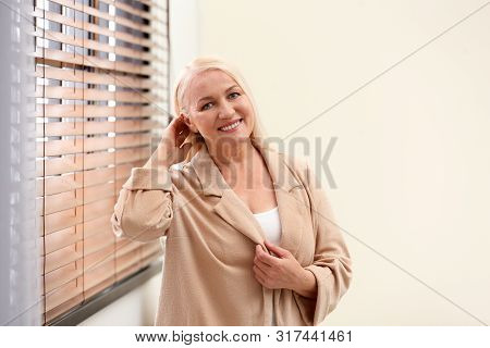 Portrait Of Happy Mature Woman Near Window Indoors