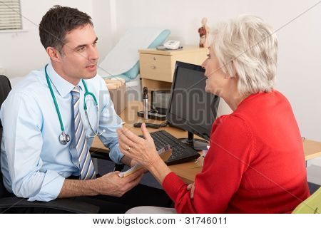 British GP talking to senior woman in surgery