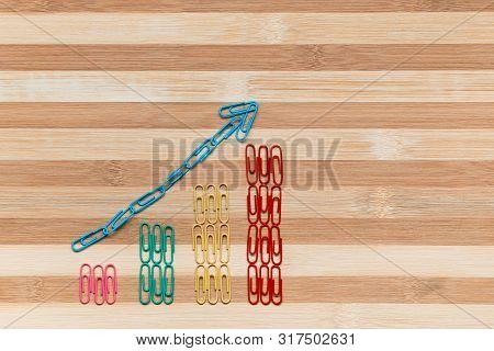 An Arrow Siting On A Bunch Of Paperclips Arranged In Columns On A Table, Shot From Above.