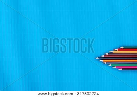 A Bunch Of Crayons On A Blue Background, Shot From Above , Arranged At The Bottom Right.