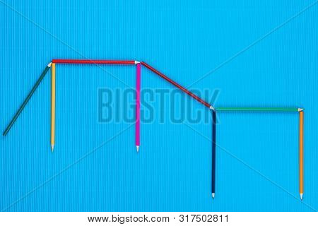 A Bunch Of Crayons Arranged In A Pattern On A Blue Background , Shot From Above.