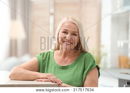 Portrait Of Happy Mature Woman At Table Indoors