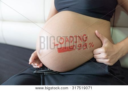 Close Up. Pregnant Woman Touching On Her Big Belly, With Loading 99% Concept Painted On Belly.