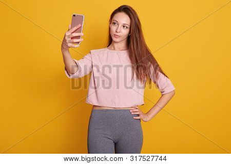Studio Shot Of Beautiful Brown Haired Woman With Straight Hair In Gray Trousers And Rose Shirt Takin