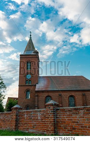 Church In Guelpe, Germany With Two Storks Breeding On The Clock Tower Roof