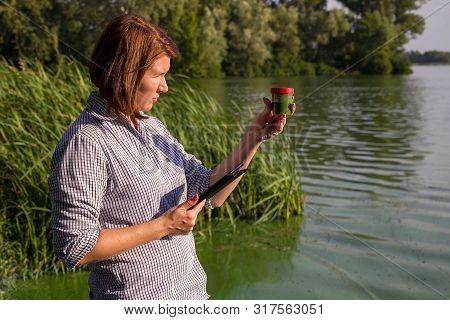 Female Researcher With Tablet Examines Sample Of River Water With Green Algae