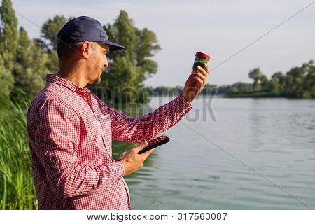 Researcher Ecologist With Tablet Examines Tube With Green Algae Outside