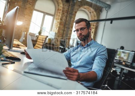 Let Me Think. Concentrated Bearded Engineer In Eyeglasses And Formal Wear Looking At Blueprint While