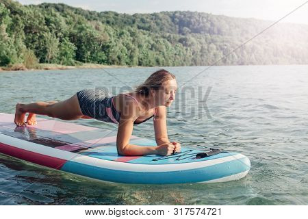 Middle Age Caucasian Woman Practicing Yoga On Paddle Sup Surfboard At Sunset. Female Stretching Doin