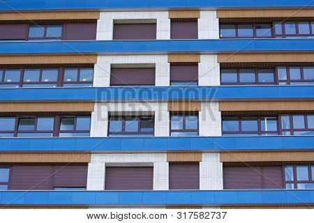 Photo Of A Buolding Facade With Several Windows, Cold Colours And Sunlight.